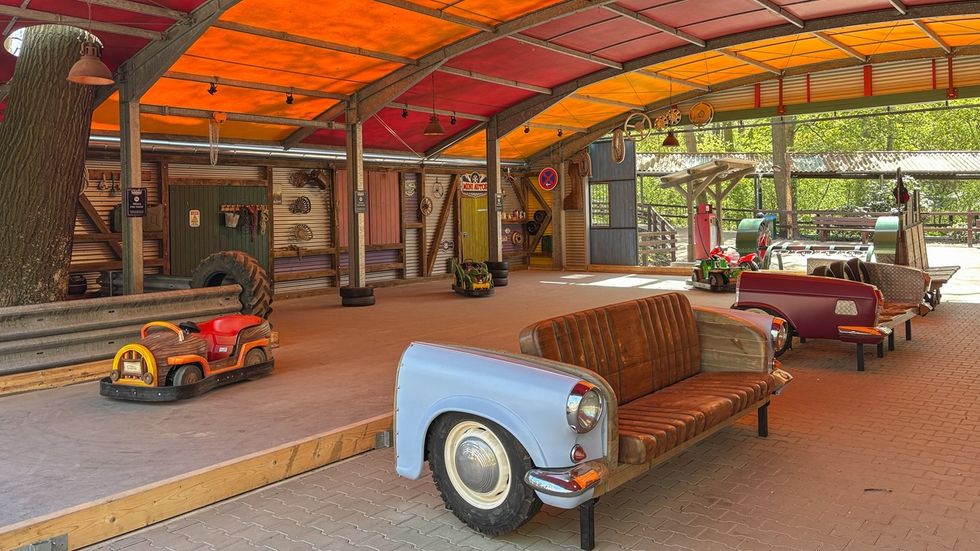 Retro-themed room with car parts as furniture under a colorful canopy.