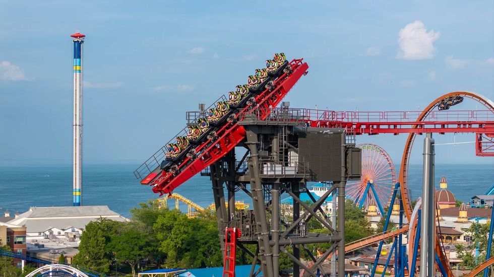 Roller coaster ascending with ocean view, Ferris wheel, and drop tower in amusement park called Cedar Point