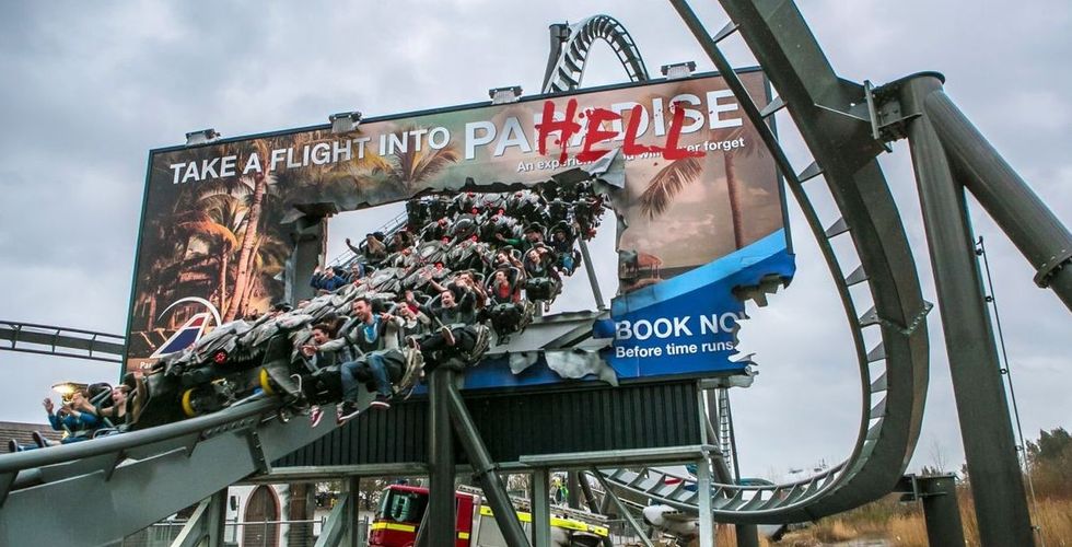 Roller coaster bursting through a "paradise" billboard, changing "paradise" to "hell".