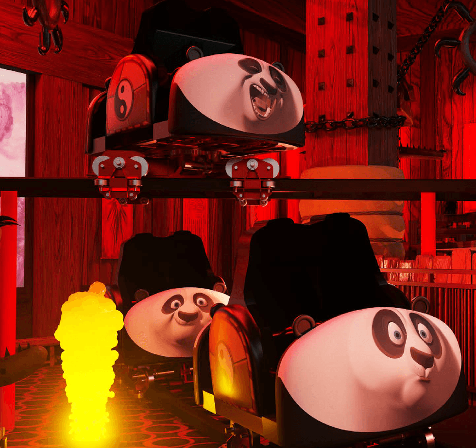Roller coaster cars shaped like pandas with expressive faces in a dimly lit room.