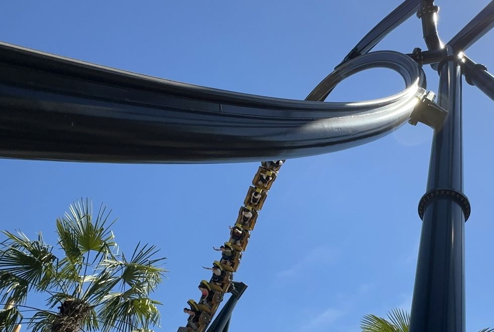 Roller coaster loop against a clear blue sky, with palm trees below at \u200bWalibi Rh\u00f4ne-Alpes