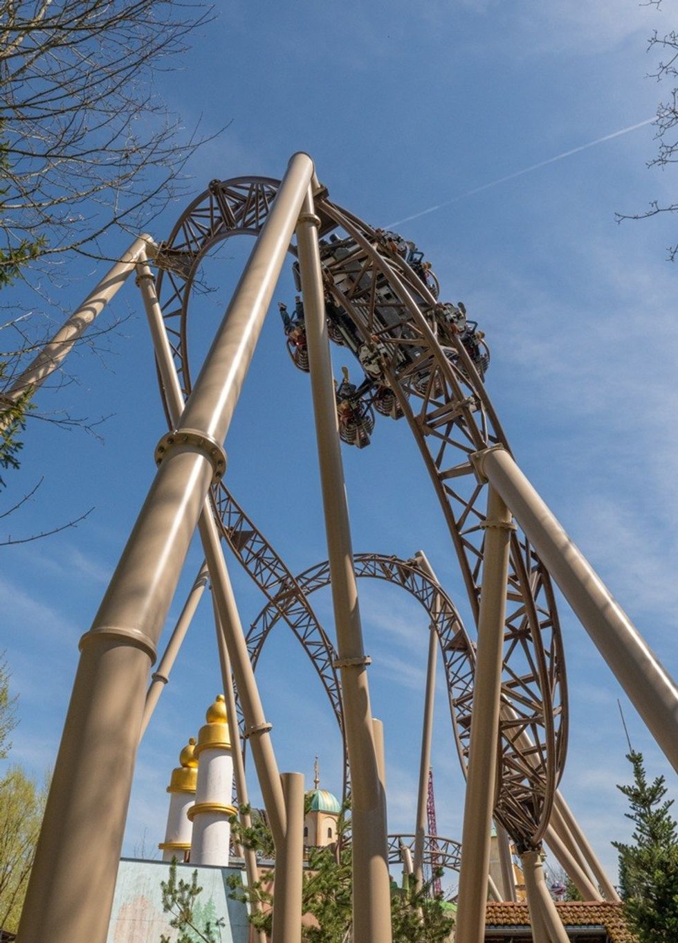 Roller coaster loop with riders against a clear blue sky.