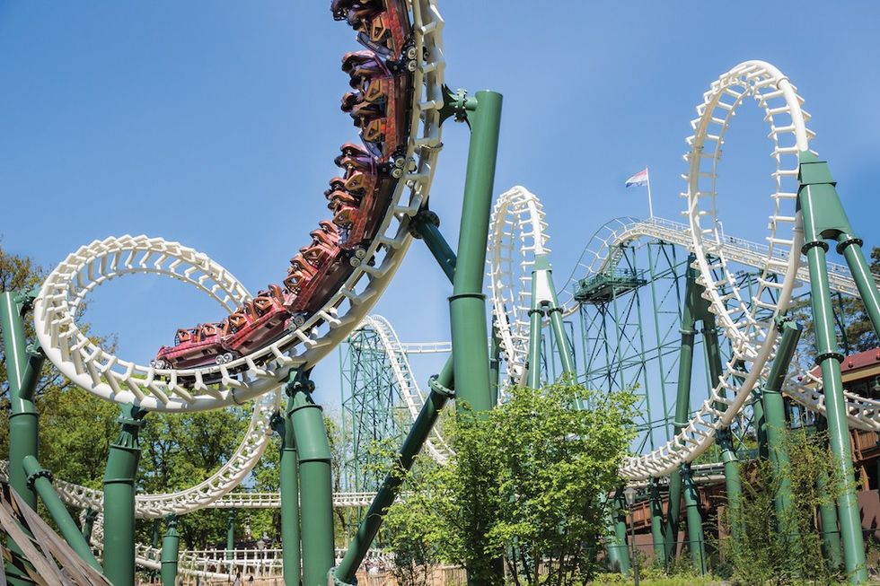 Roller coaster looping on a sunny day with trees and blue sky at Efteling