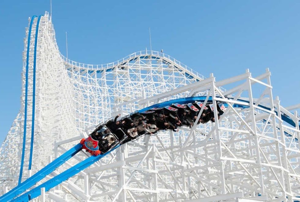 Roller coaster on a steep curve with blue skies and white track structure.