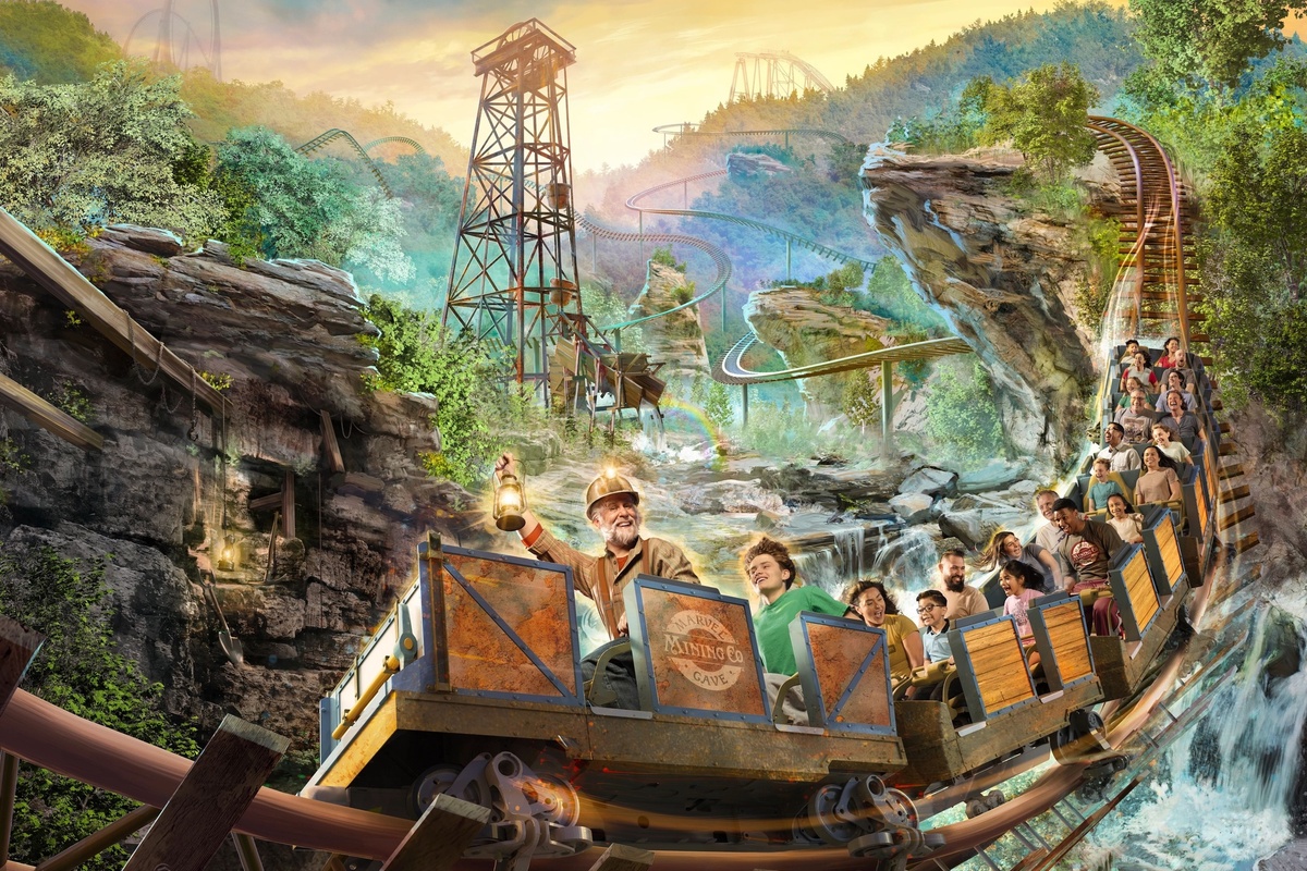 Roller coaster ride through forested mountains with excited passengers and a miner character at Silver Dollar City