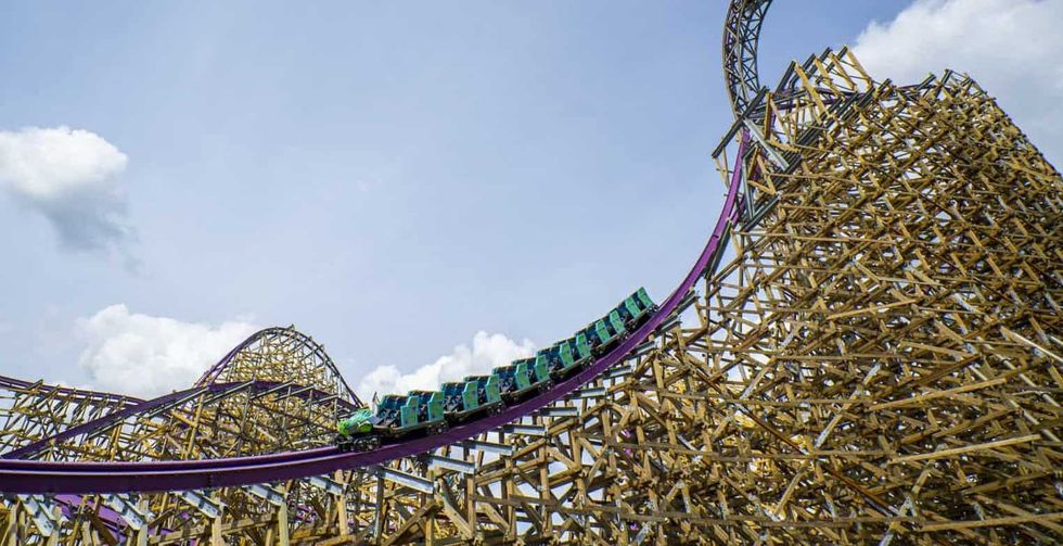 Roller coaster with green cars on a wooden track against a cloudy sky at Busch Gardens Tampa Bay