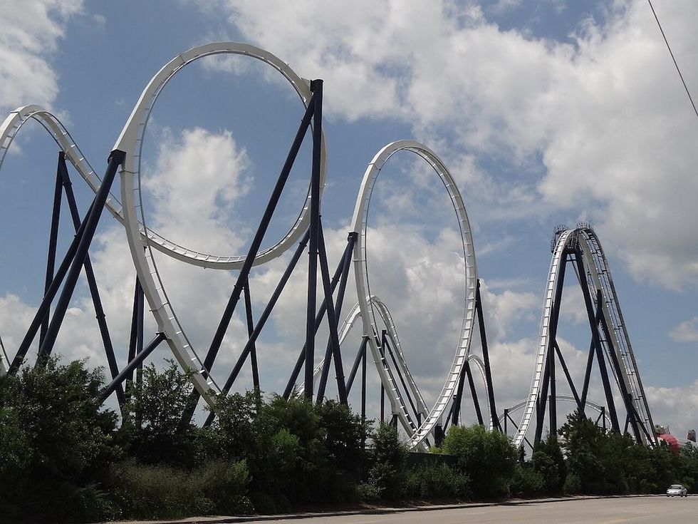 Roller coaster with tall loops against a cloudy sky.