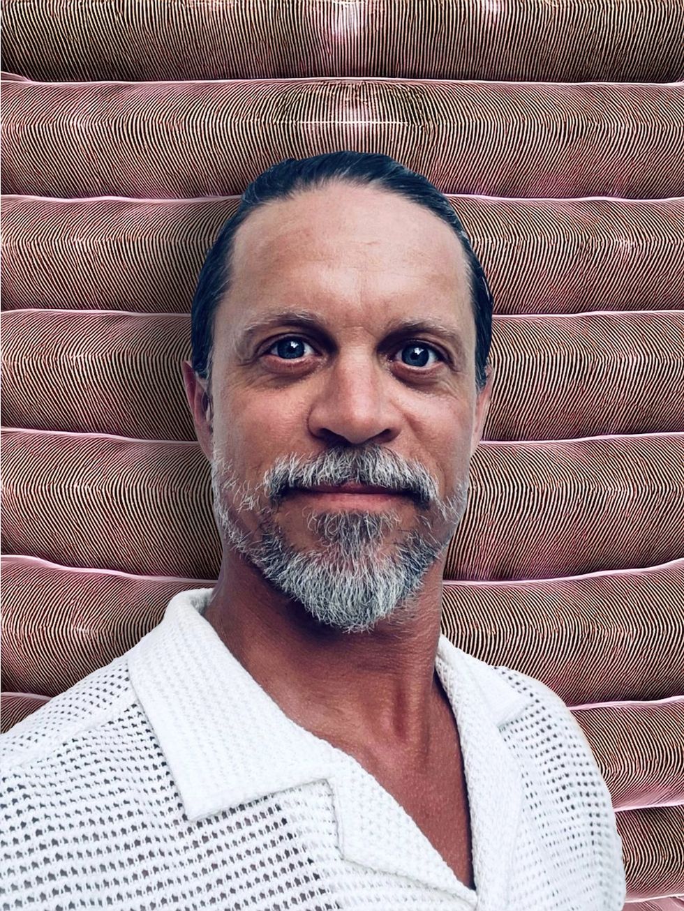 Roman Beranek in a white shirt against a textured, pink and brown striped background.