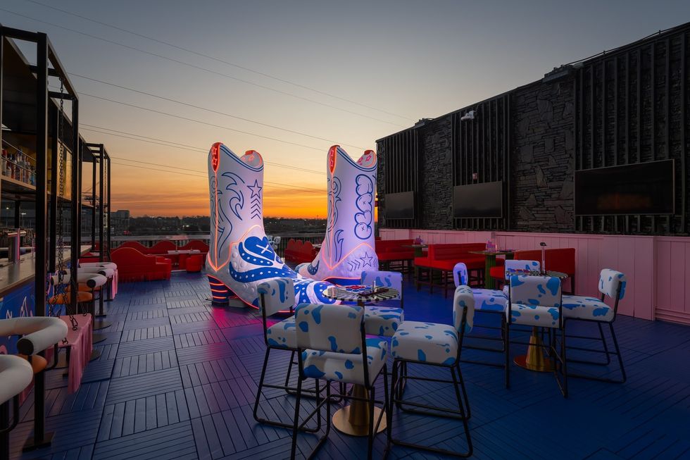 Rooftop with giant illuminated boots, cow-print chairs, at sunset, at Play Playground