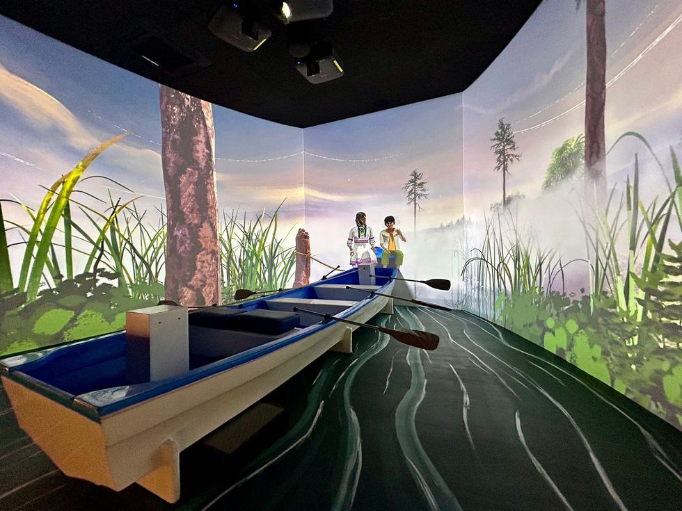 Room with a boat and immersive nature projections on surrounding walls.