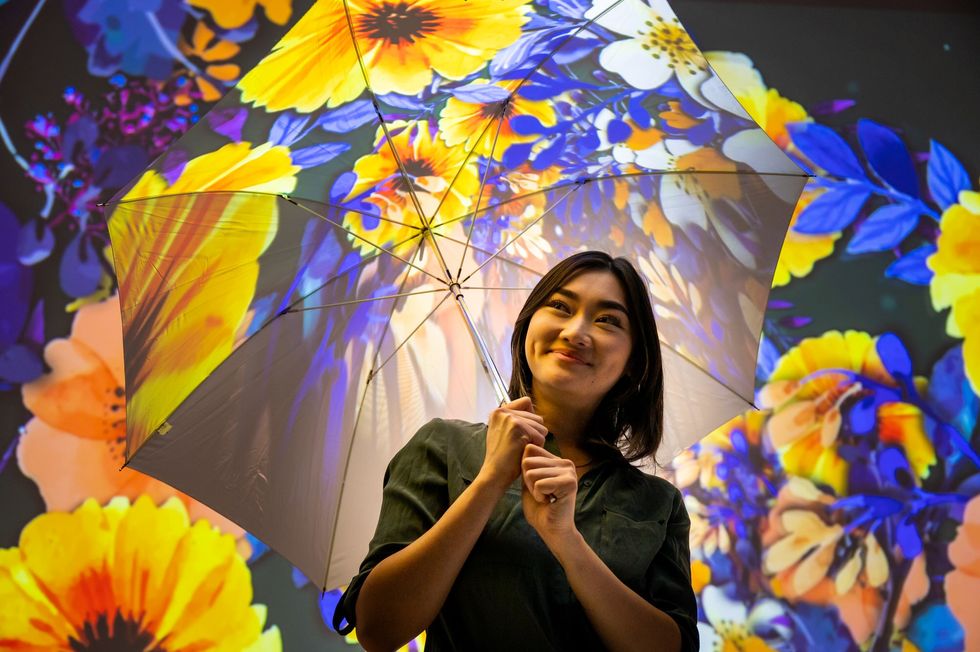 ROTO. Woman holding umbrella with sunflower projections