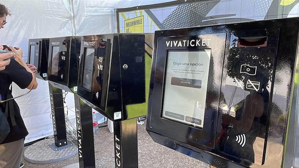 Row of VivaTicket kiosks with screens under a white tent.