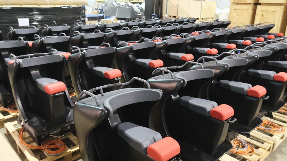 Rows of black and red cinema seats on wooden pallets in a warehouse.