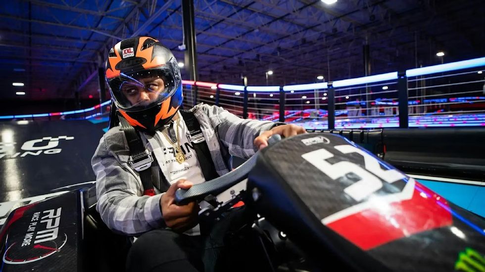 RPM Raceway's Kart Klash Person in a helmet driving a go-kart on an indoor track.
