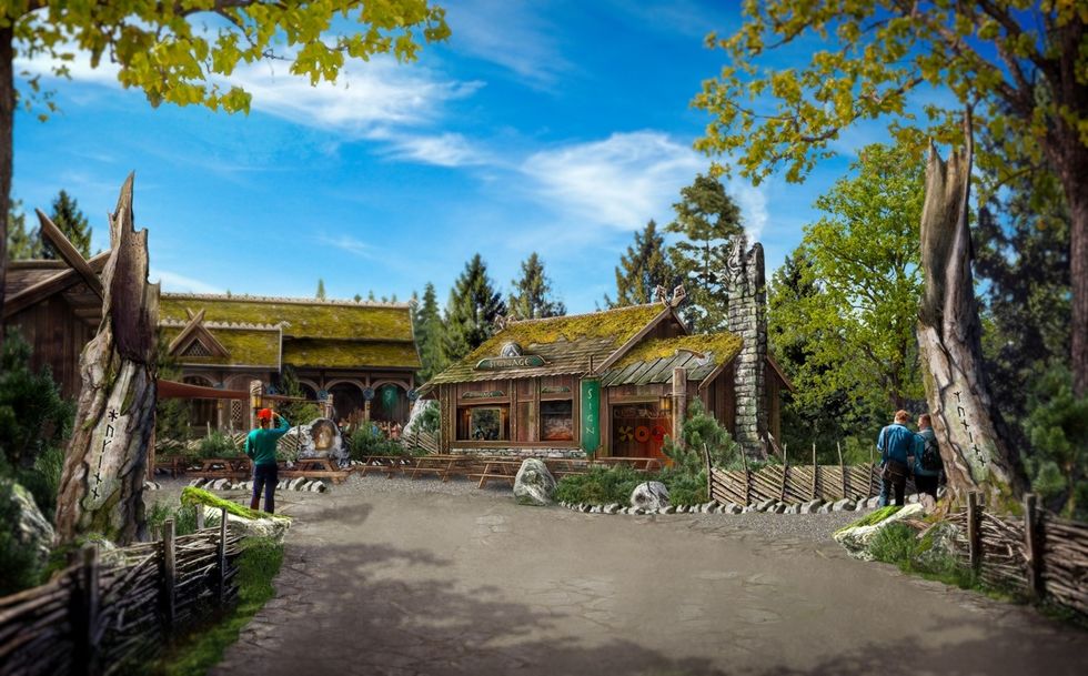 Rustic buildings at Djurs Sommerland surrounded by trees and wooden fences under a clear blue sky.