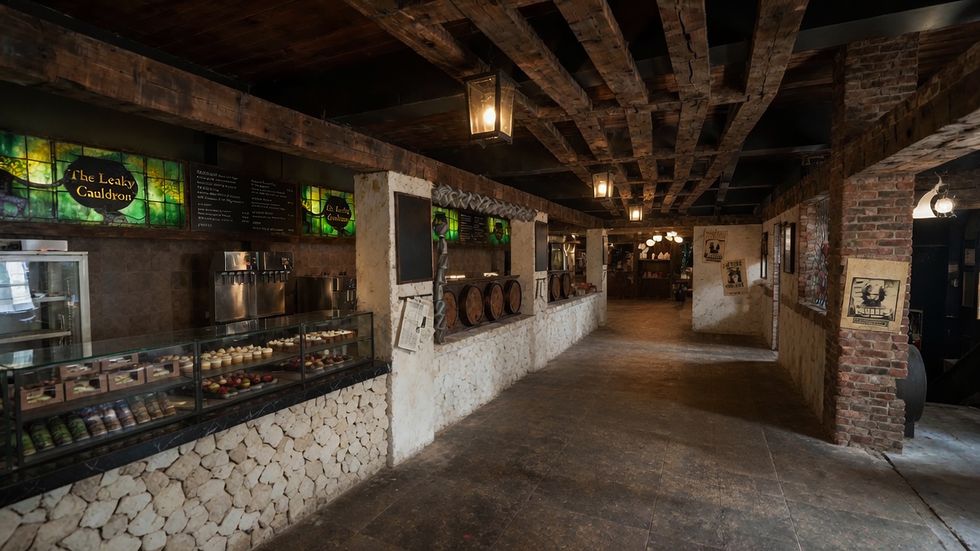 Rustic tavern interior with stone walls, wooden beams, and dessert display counter.