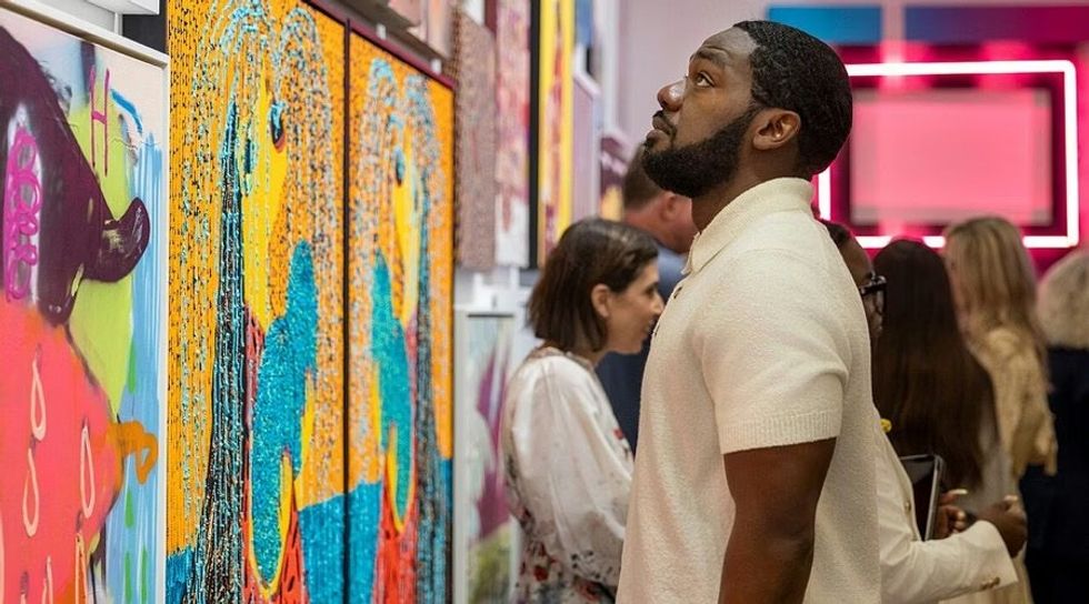 SCADstory Atlanta Man observing colorful abstract art, with others in the background.