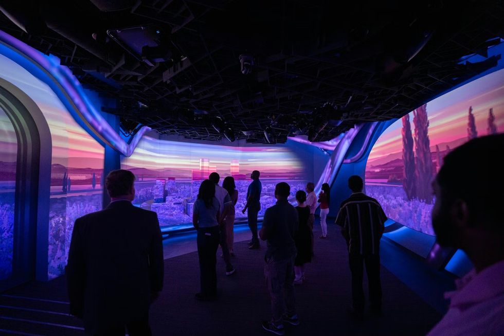 SCADstory Atlanta People observe colorful digital projections in a dimly lit immersive gallery.