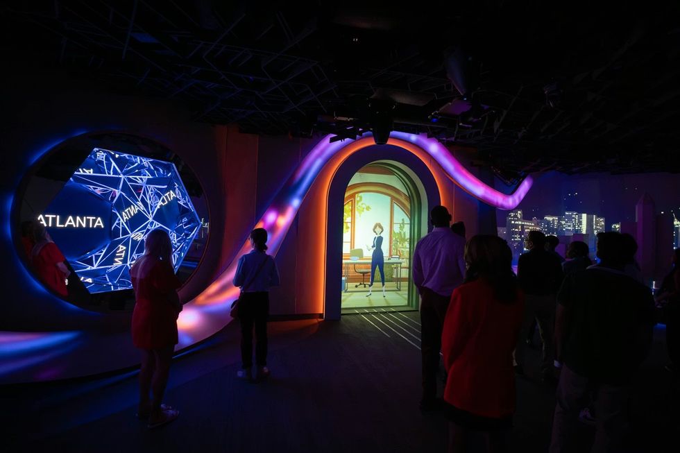 SCADstory Atlanta People viewing a vibrant digital installation in a dimly lit space.