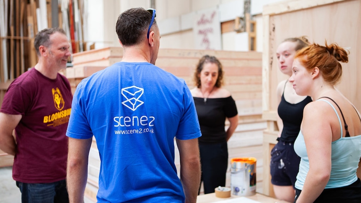 Scene2 team discussing in a workshop, surrounded by wooden structures.