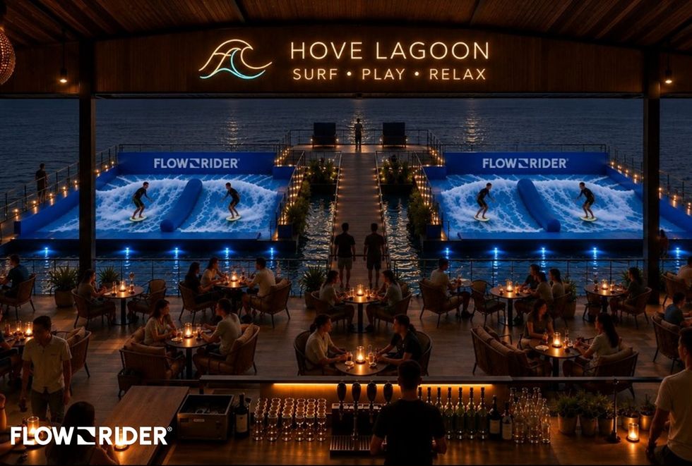 Scenic view of indoor surfing at night with diners and illuminated waves at Hove Lagoon