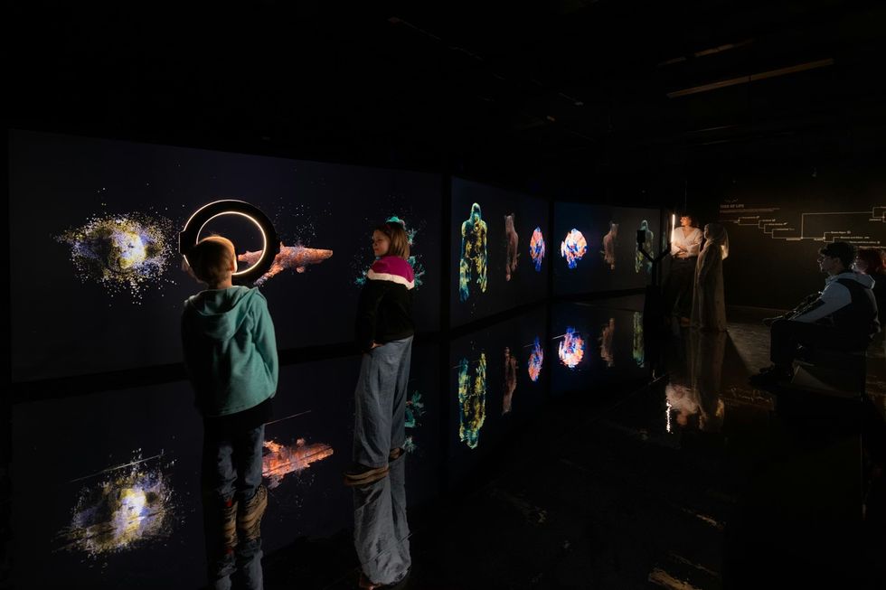 Science Museum Group - YOU:MATTER. People viewing digital art displays in a dark, reflective gallery space.