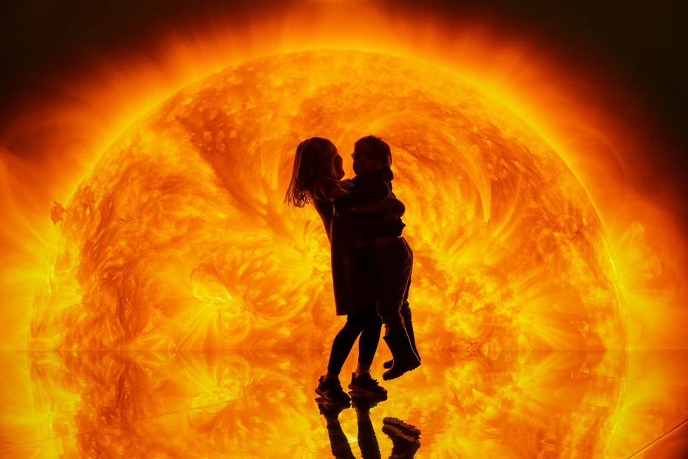 Science Museum Group - YOU:MATTER. Silhouettes of two children hugging in front of a large, bright orange sun.