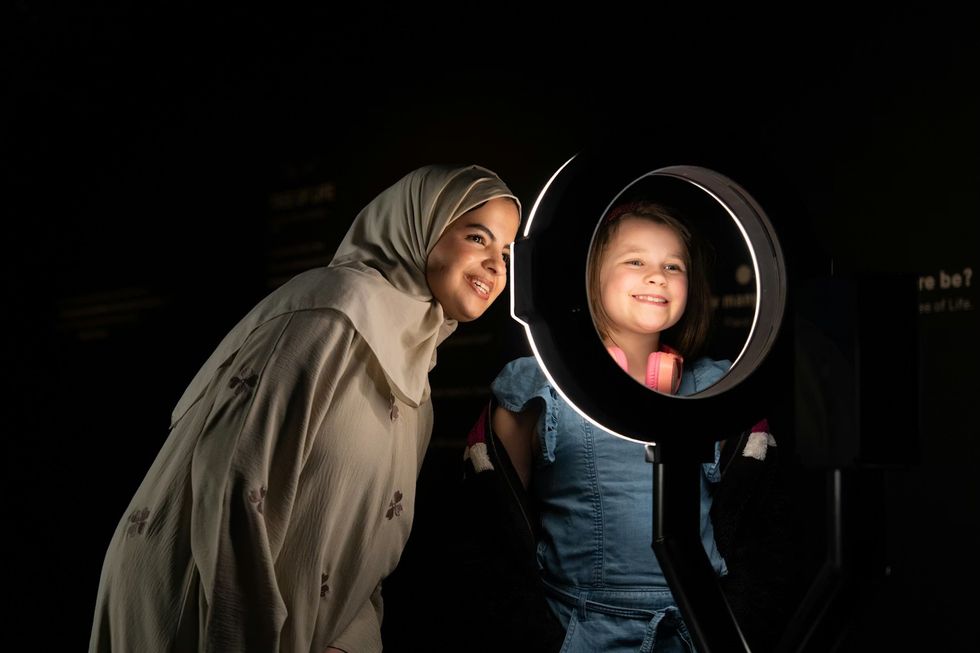 Science Museum Group - YOU:MATTER. Woman and girl smiling, illuminated by a ring light in a dark room.