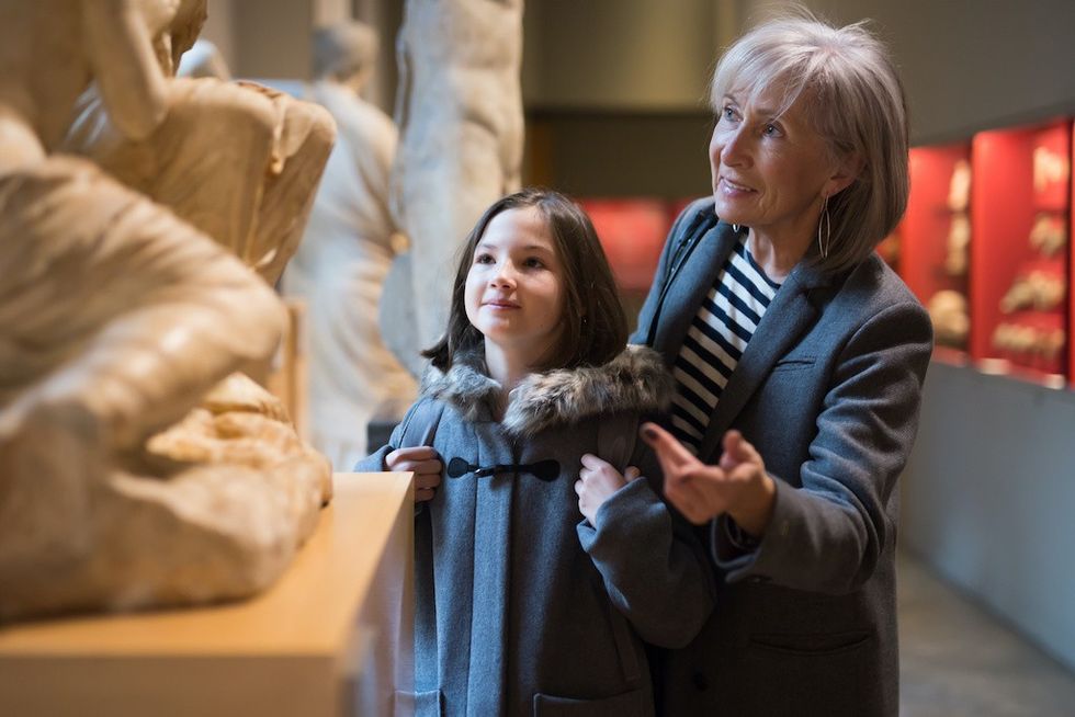 Senior woman and preteen girl viewing ancient sculptures in museum
