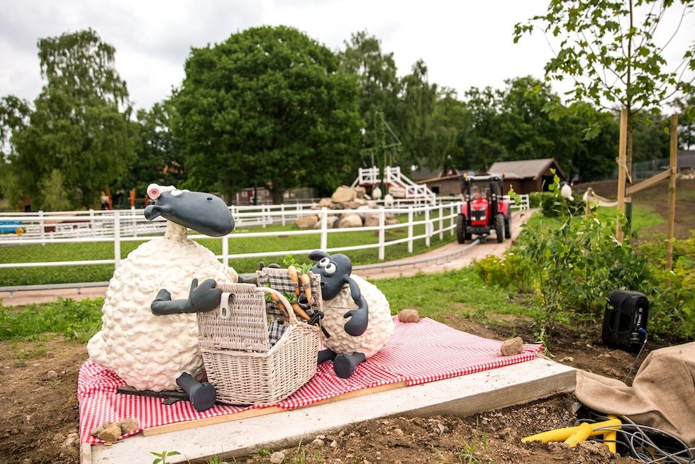 Shaun the Sheep having a picnic on a red blanket, with a tractor in the background.