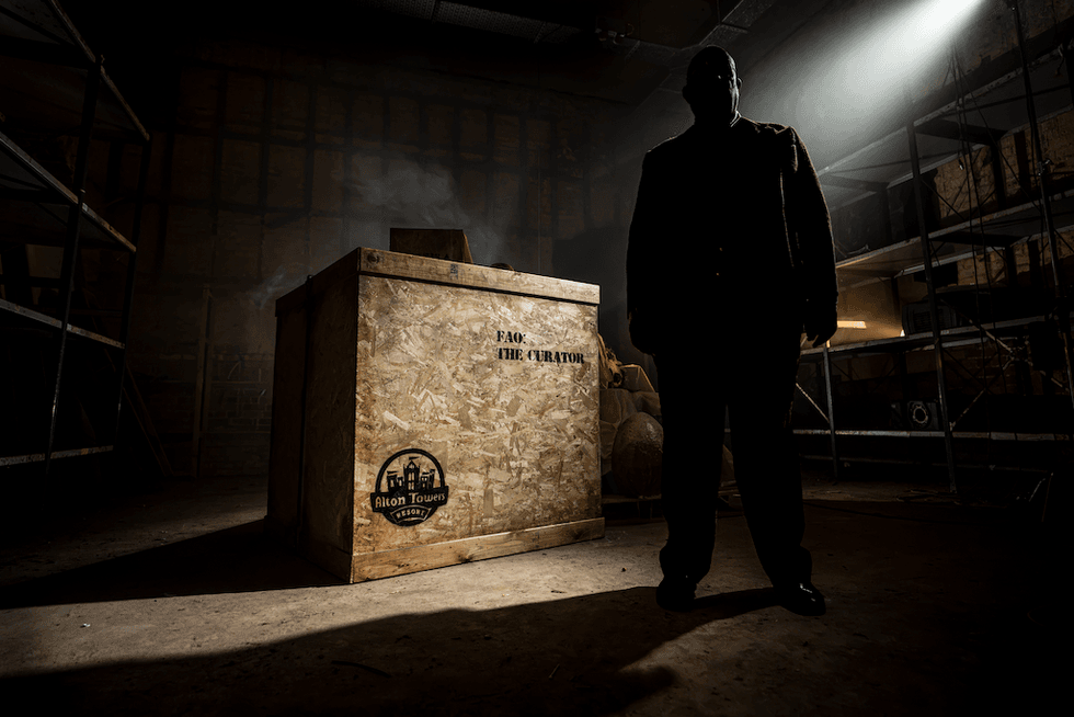 Silhouette of a man next to a large crate with "For the Curator" text in a dimly lit room.