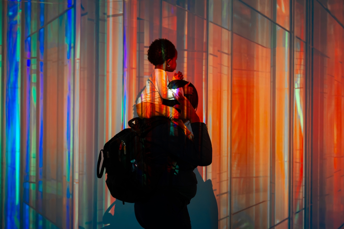 Silhouette of a parent with child against a colorful, abstract light background.
