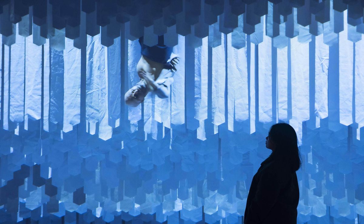 Silhouette of a person gazing at an abstract, geometric blue installation - Akram Khan’s DESH, 2011