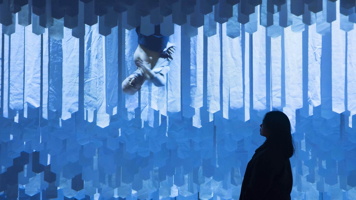 Silhouette of a person gazing at an abstract, geometric blue installation - Akram Khan’s DESH, 2011