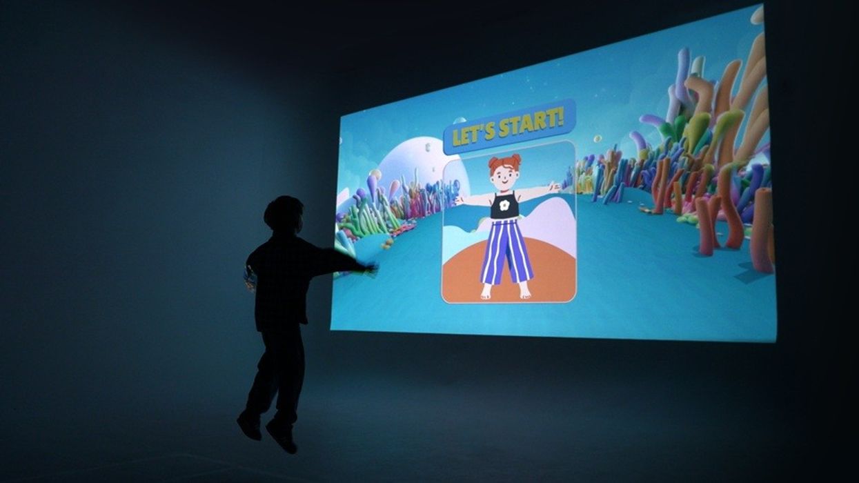 Silhouette of child interacting with a colorful digital game projection.