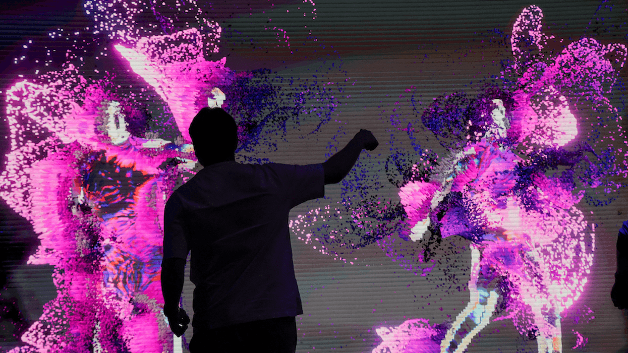Silhouette of person interacting with vibrant pink and purple digital art display.
