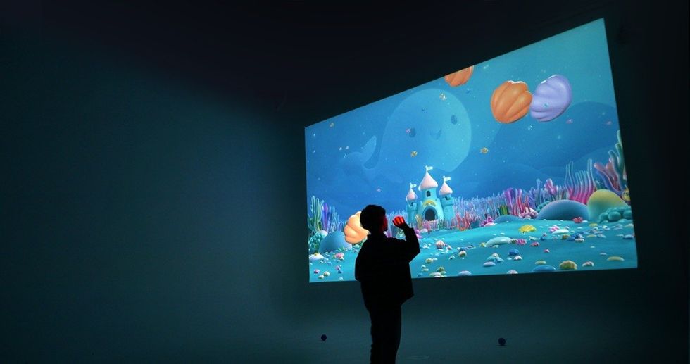 Silhouette of person viewing animated underwater scene projected on a screen.