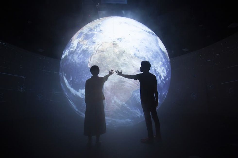 Silhouette of visitors in front of projected globe