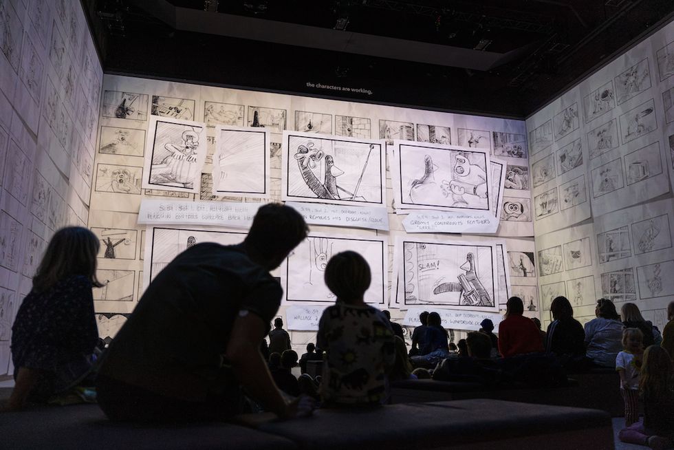 Silhouetted audience watching storyboards on a large screen in a dark room.
