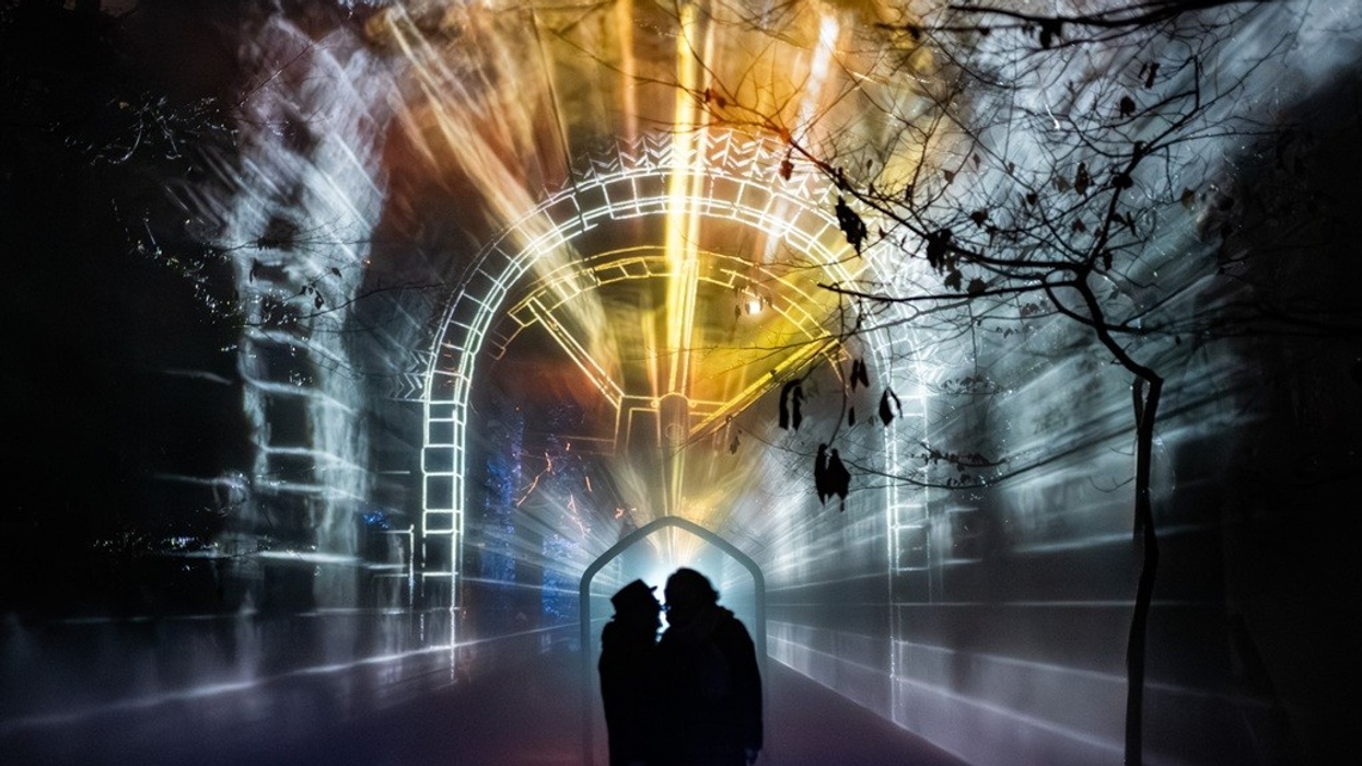 Silhouetted couple under a colorful, illuminated archway at night.