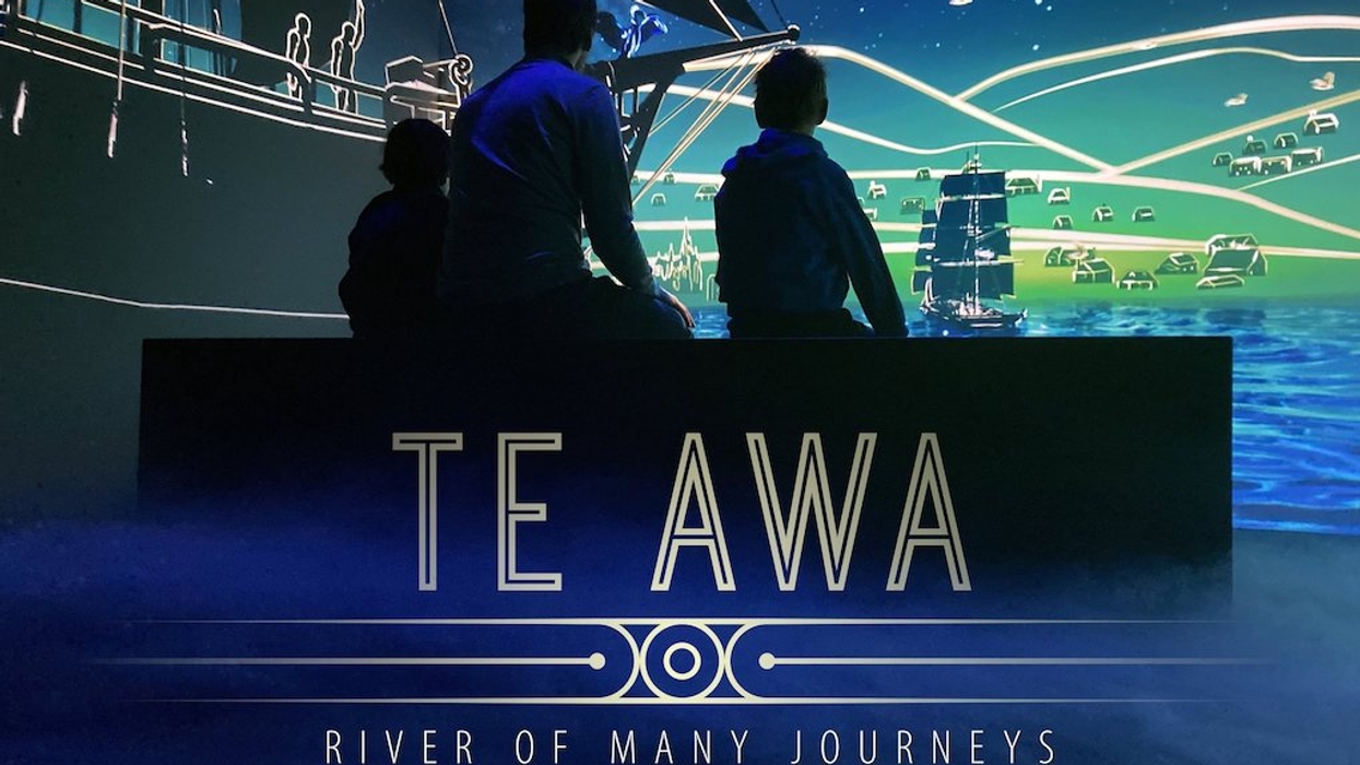 Silhouetted figures in front of a screen displaying ships, "Te Awa: River of Many Journeys."