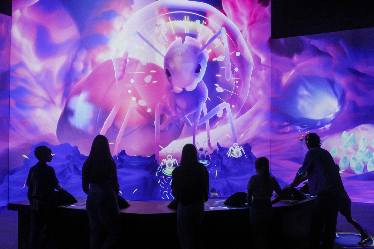 Silhouetted people enjoy a vibrant, immersive digital display with large, abstract insect art, Antopia by S1T2