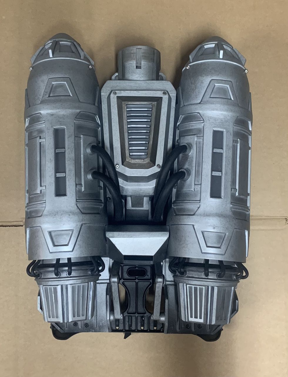 Silver sci-fi jetpack with twin cylindrical boosters on a cardboard background.