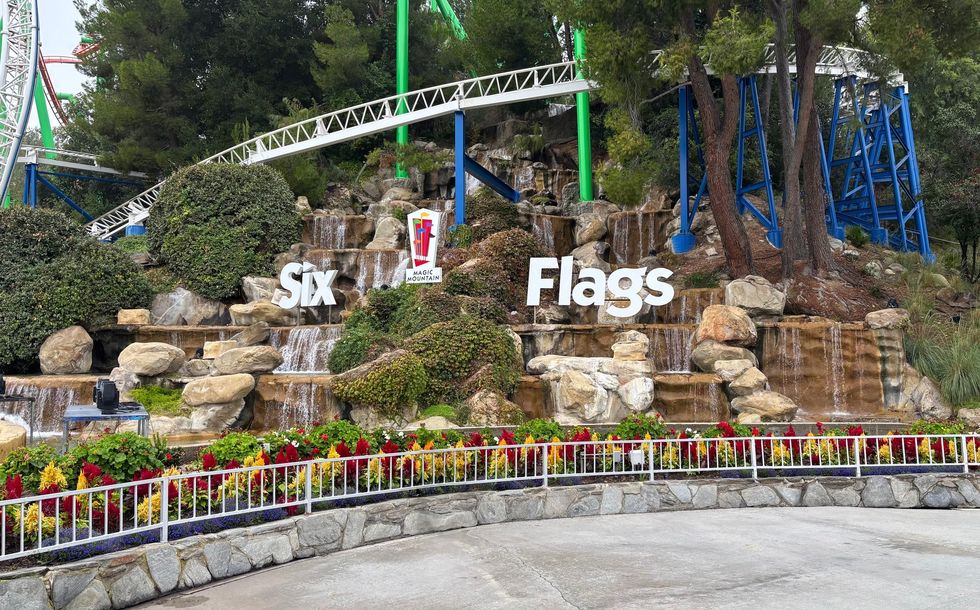 Six Flags Magic Mountain entrance with waterfalls and colorful flowers.