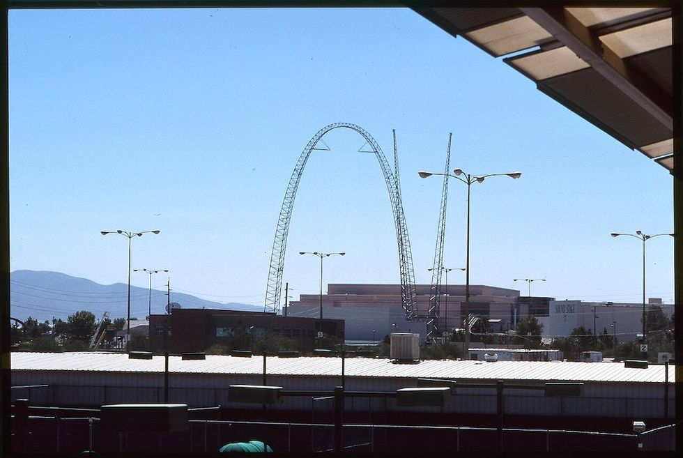 Skycoaster ride structure against a clear blue sky with mountains in the background.