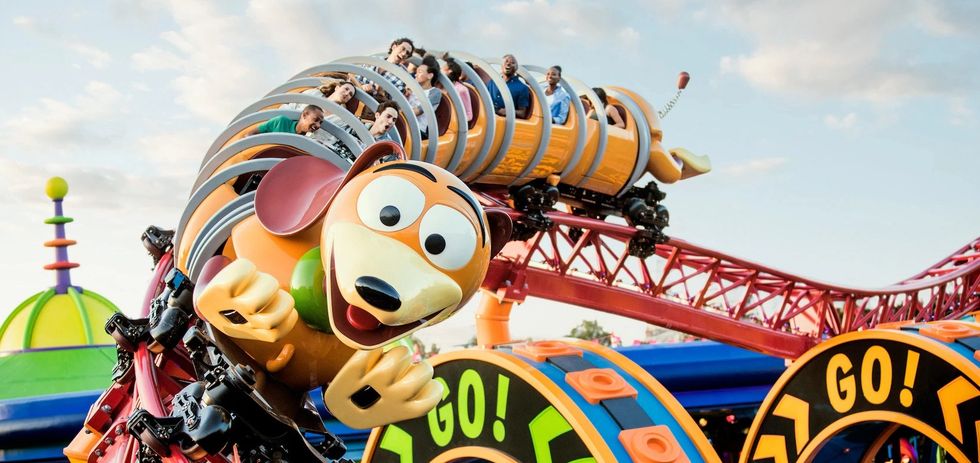 Slinky Dog-themed roller coaster with excited riders at an amusement park called Disney's Hollywood Studios