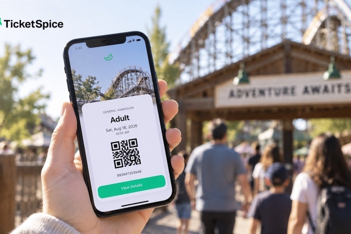 Smartphone displaying digital ticket from TicketSpice near amusement park entrance.