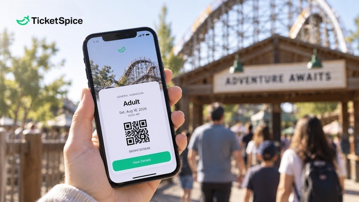 Smartphone displaying digital ticket from TicketSpice near amusement park entrance.