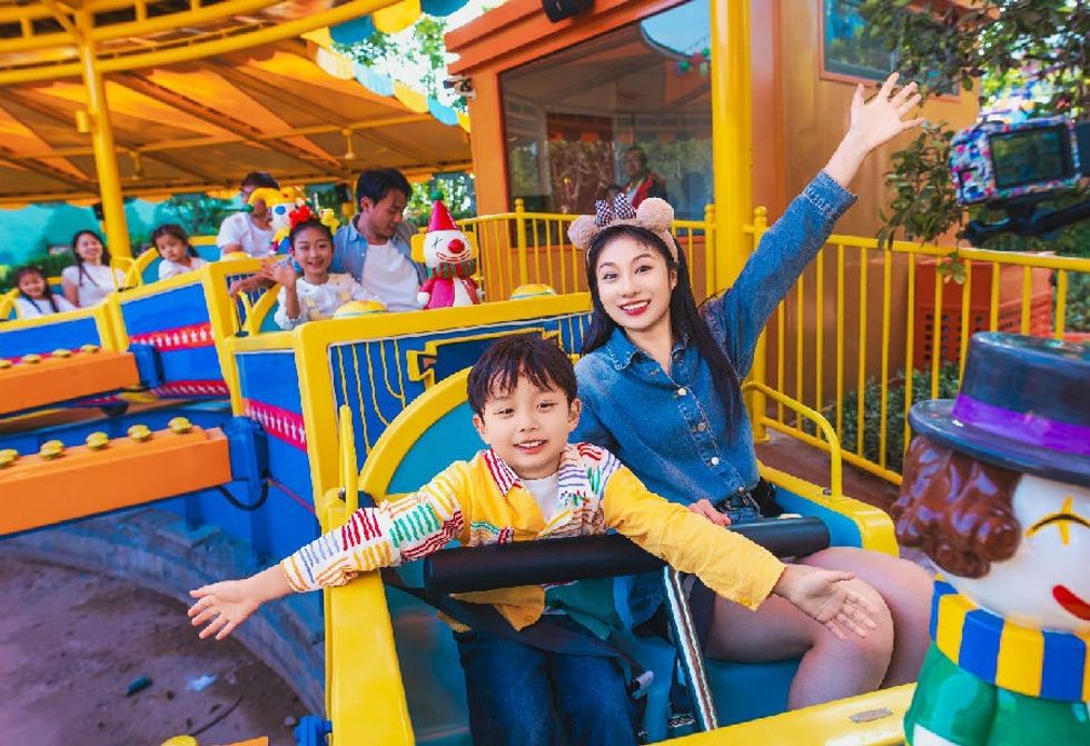 Smiling child and woman enjoying a colorful amusement park ride at Boonie Bears land