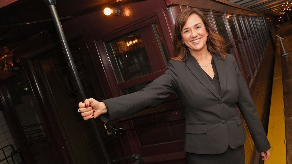 Smiling Concetta Bencivenga hanging from the end of a stationary train